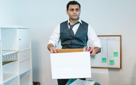 Professional man organizing office belongings in a cardboard box, preparing for transition.