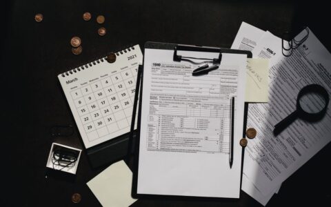 A neatly organized workspace featuring tax forms, calendar, magnifying glass, and office supplies for efficient tax preparation.