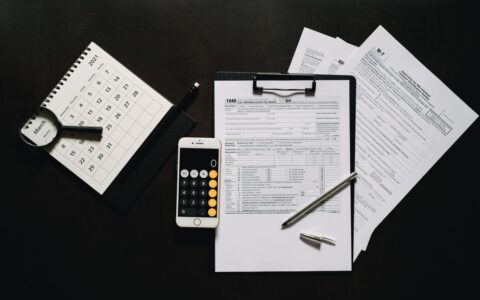 Flat lay of financial tools for tax preparation including forms, calculator, and calendar.