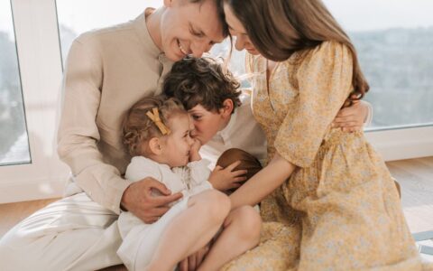 A happy family of four sitting together and sharing a loving moment indoors.