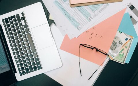 A tidy workspace featuring a laptop, documents, and eyeglasses for productivity.