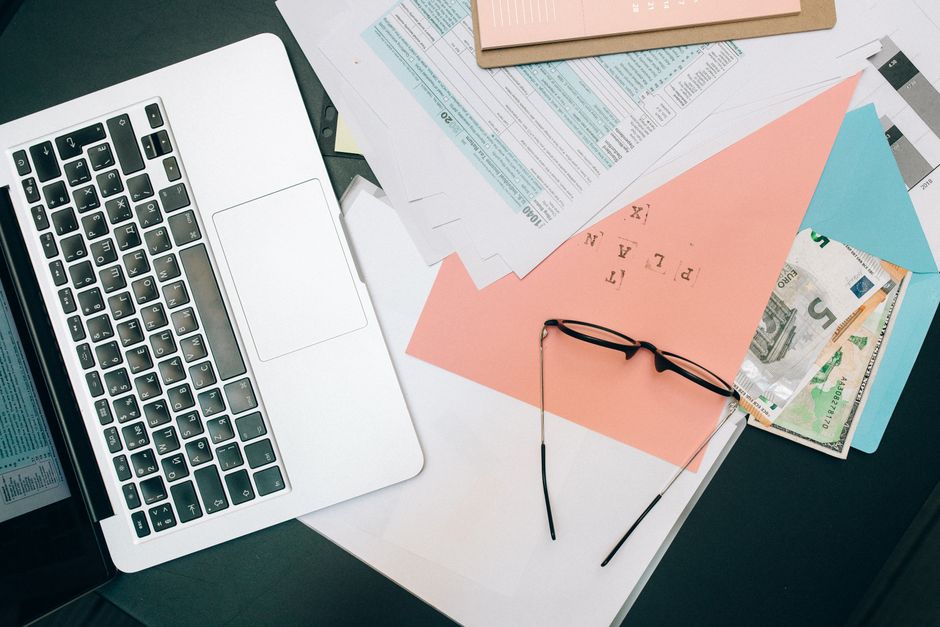 A tidy workspace featuring a laptop, documents, and eyeglasses for productivity.